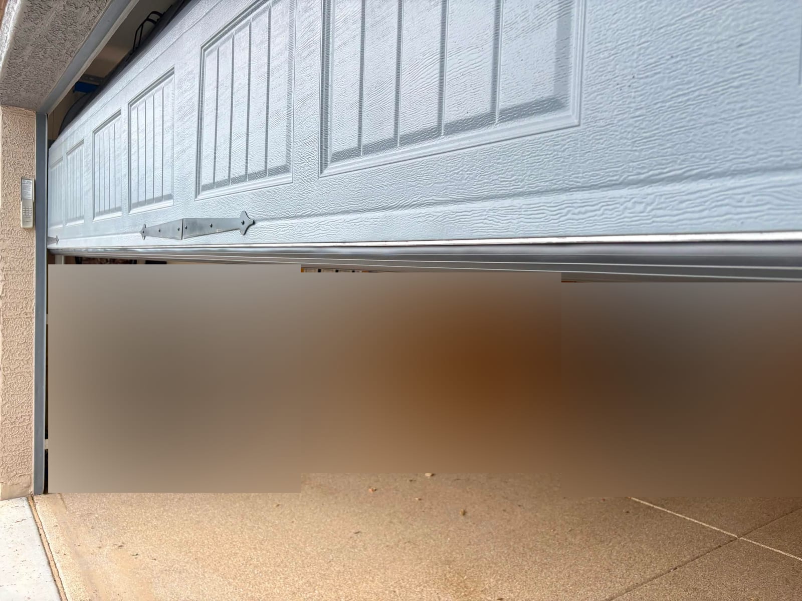 After: new aluminum universal retainer and bottom seal along the lower edge of a garage door, seen from inside the garage in Gilbert