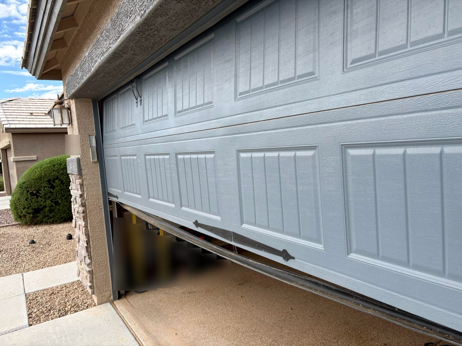 Before: cracked and deteriorating bottom seal along the lower edge of a garage door, seen from the driveway in Gilbert